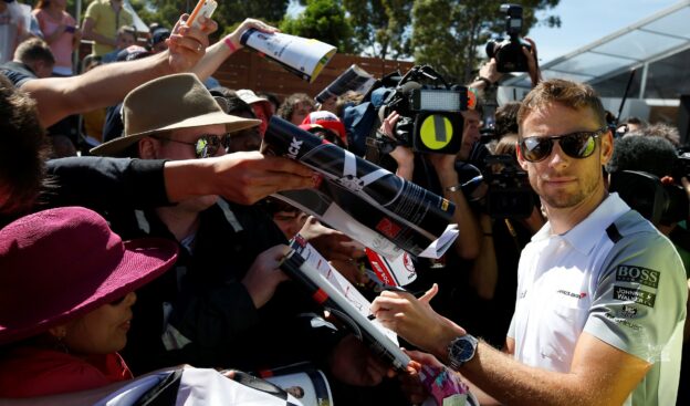 Jenson Button signs autographs for fans.