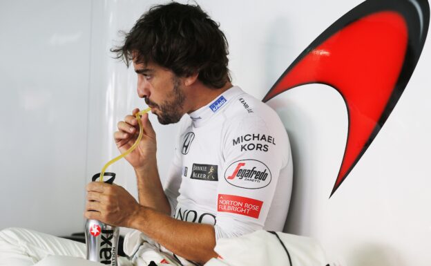 Fernando Alonso takes a drink in the pit garage.