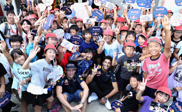 SUZUKA, JAPAN - OCTOBER 06: Daniel Ricciardo of Australia and Red Bull Racing and Max Verstappen of Netherlands and Red Bull Racing with some elementary school children in the Pitlane during previews ahead of the Formula One Grand Prix of Japan at Suzuka Circuit on October 6, 2016 in Suzuka. (Photo by Mark Thompson/Getty Images)