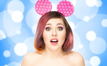 Beautiful young smiling woman in mickey mouse ears on bubble background.