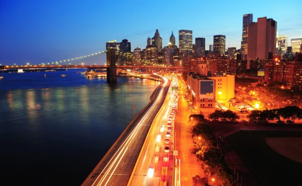 New york city manhattan downtown skyline aerial view at dusk with skyscrapers lit over east river with reflections.